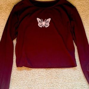A long sleeved, dark brown crop top with a white butterfly